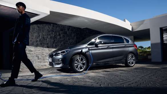 Priključni hibrid BMW 225xe Active Tourer, F45, tričetrtinski stranski pogled pred stavbo Priključni hibrid BMW 225xe Active Tourer, F45, tričetrtinski stranski pogled pred stavbo z manekenko