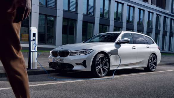 BMW serije 3 Touring, G21, 2021, priključni hibrid BMW, tričetrtinski pogled od spredaj med polnjenjem BMW serije 3 Touring, G21, 2021, priključni hibrid BMW, tričetrtinski pogled od spredaj, polnjenje pred stavbo