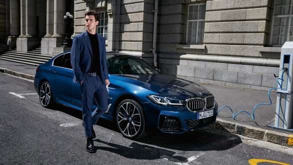 BMW serije 5 Limuzina, priključni hibrid, 2021, G30, tričetrtinski pogled od spredaj med polnjenjem BMW serije 5 Limuzina, priključni hibrid, 2021, G30, tričetrtinski pogled od spredaj med polnjenjem z manekenko