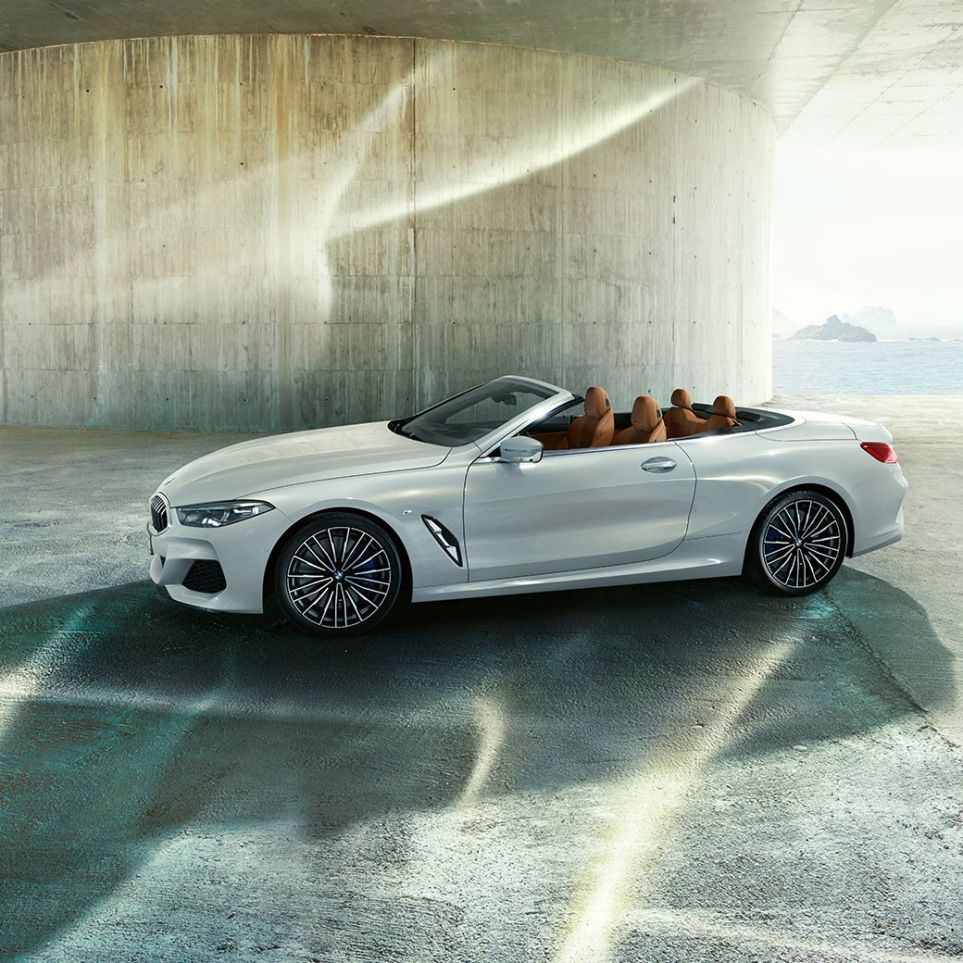 BMW M850i xDrive v kovinskem odtenku Mineral White, pogled s strani z odprto mehko streho. BMW M850i xDrive v kovinskem odtenku Mineral White, pogled s strani z odprto mehko streho.