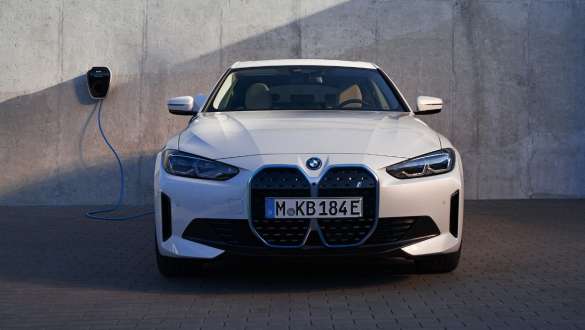 BMW i4 eDrive40, G26, 2021, pogled od spredaj BMW i4 eDrive40, G26, 2021, barva Mineral White, pogled od spredaj na steno hiše s polnilno postajo BMW Wallbox