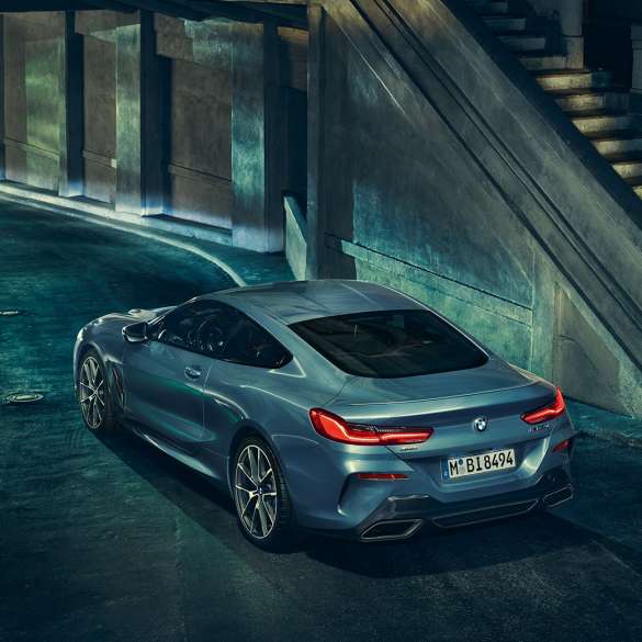 BMW M850i xDrive Coupé, v zadnjem polprofilu z leve strani. BMW M850i xDrive Coupé v kovinski barvi Barcelona Blue, v zadnjem polprofilu, parkiran ponoči.
