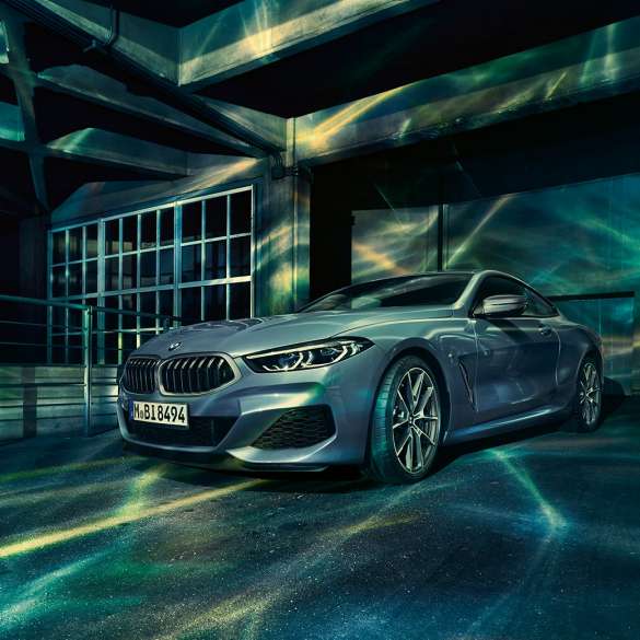 BMW M850i xDrive Coupé, v sprednjem polprofilu. BMW M850i xDrive Coupé v kovinski barvi Barcelona Blue, v sprednjem polprofilu, parkiran pred stavbo.