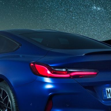 M zadnji spojler BMW M8 Competition Coupé v kovinski barvi Marina Bay Blue, povečan nočni posnetek ramenskega dela z M zadnjim spojlerjem v barvi Carbon.