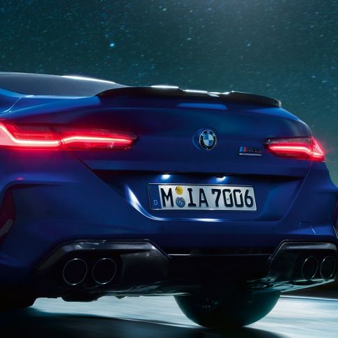 M difuzor v barvi Carbon Black. BMW M8 Competition Coupé v kovinski barvi Marina Bay Blue, povečan posnetek zadnjega dela ponoči z M difuzorjem v barvi Carbon Black.