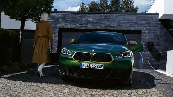 BMW X2 xDrive25e, F39, priključni hibrid BMW, pogled od spredaj pred garažo BMW X2 xDrive25e, F39, priključni hibrid BMW, pogled od spredaj pred garažo z manekenko