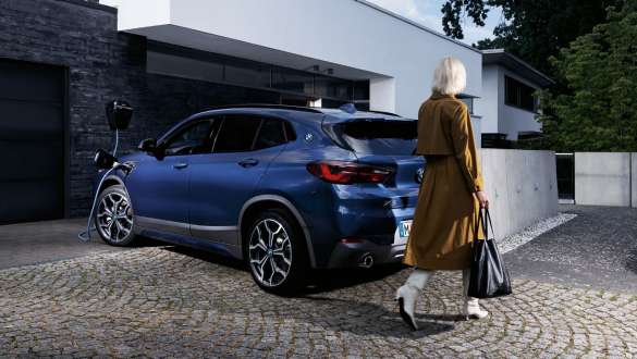 BMW X2 xDrive25e, F39, priključni hibrid BMW, tričetrtinski pogled od zadaj med polnjenjem BMW X2 xDrive25e, F39, priključni hibrid BMW, tričetrtinski pogled od zadaj med polnjenjem z manekenko