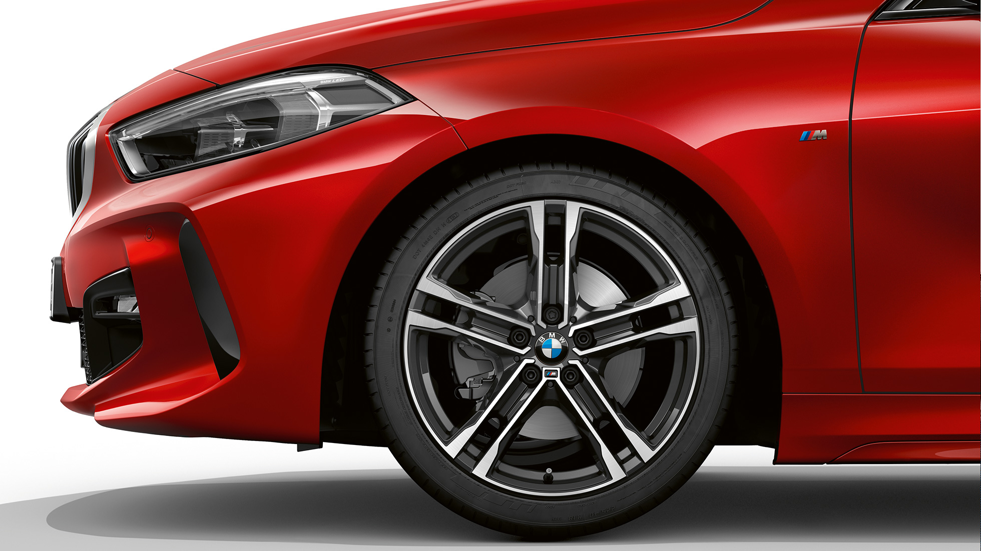BMW serije 1 kot model M Sport, stranski pogled od spredaj. BMW serije 1 kot model M Sport v kovinski barvi Melbourne Red, stranski pogled od spredaj s 17-palčnimi M litimi alu. platišči Double-spoke 550 M dvobarvne izvedbe.