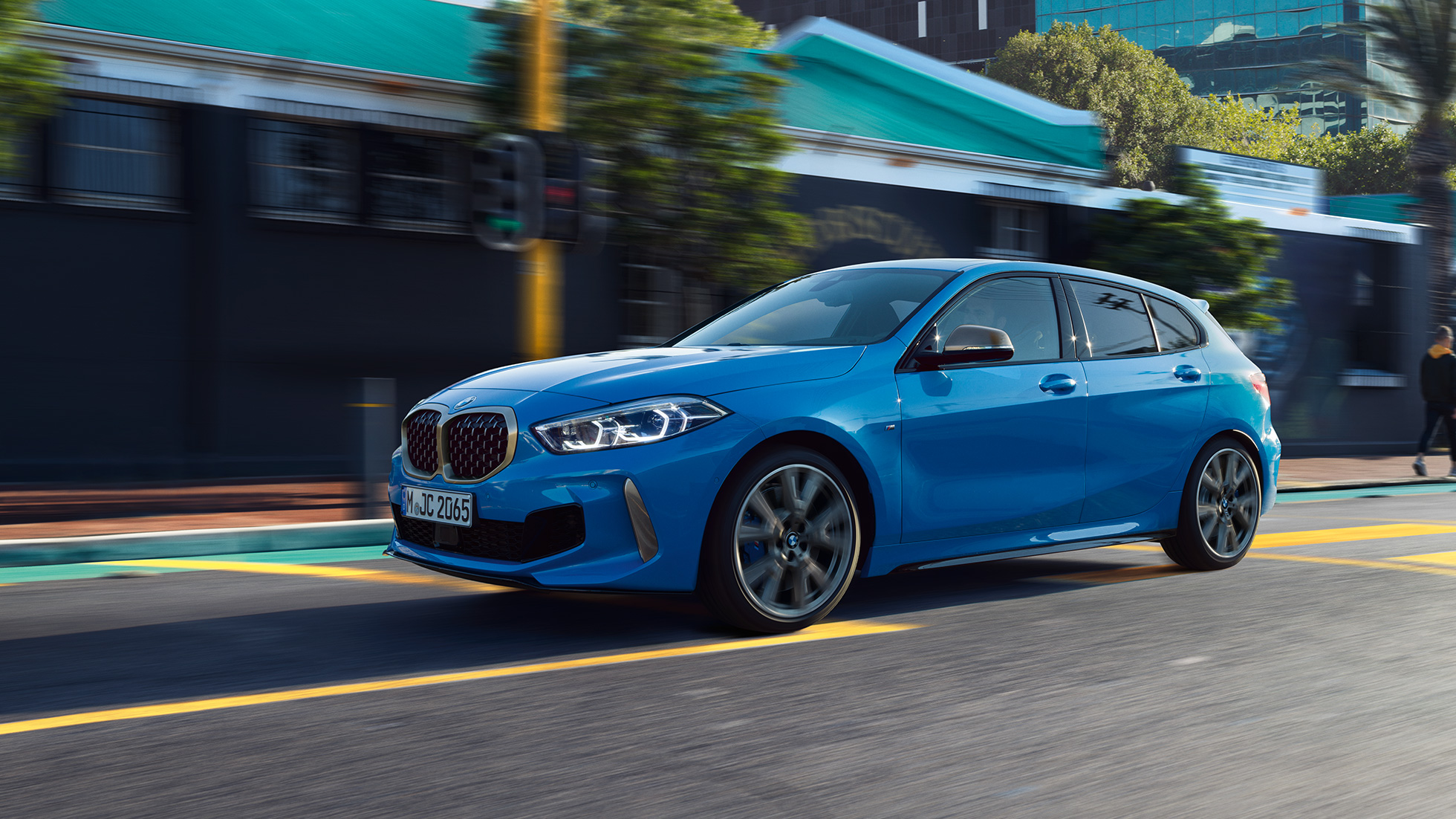 BMW serije 1, tričetrtinski stranski pogled. BMW serije 1 v kovinski barvi Misano Blue, tričetrtinski pogled od spredaj med vožnjo.