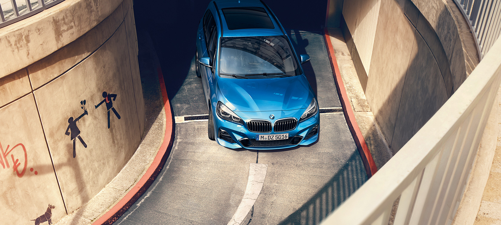 BMW serije 2 Gran Tourer med vožnjo v parkirni hiši BMW serije 2 Gran Tourer, F46, kovinska barva Misano Blue, pogled iz ptičje perspektive v parkirni hiši