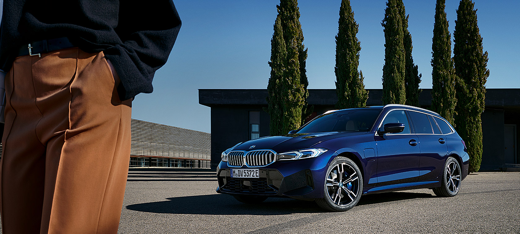 BMW serije 3 Touring, LCI, G21, barva Tansanit Blue II, tričetrtinski pogled od spredaj med mirovanjem pred drevesi