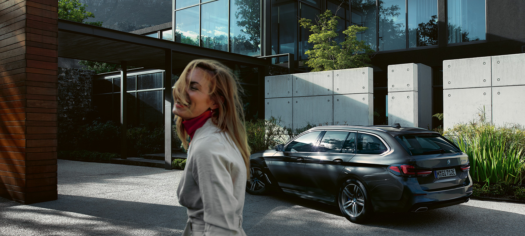 Ženska stoji pred parkiranim BMW serije 5 Touring BMW serije 5 Touring, G31, osvežitev 2020, ženska stoji pred parkiranim BMW