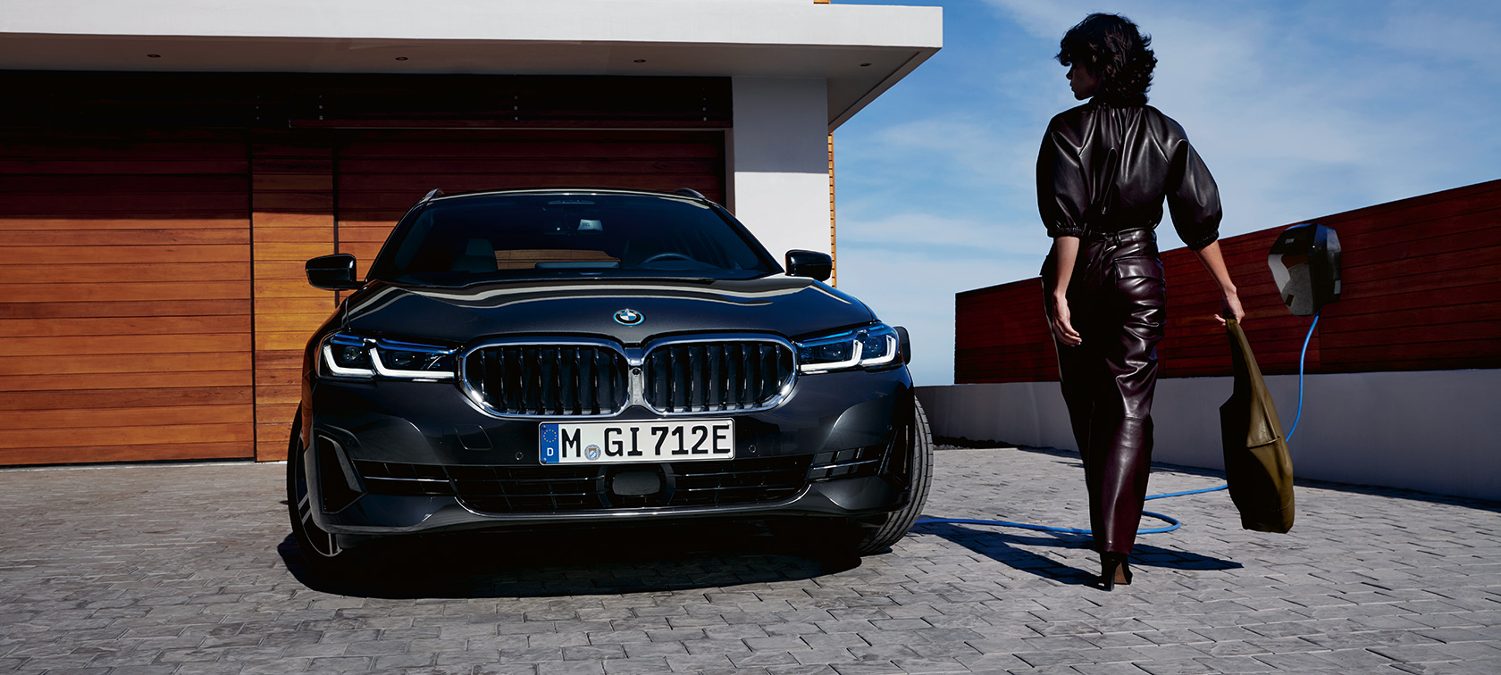 BMW serije 5 Touring, G31, LCI, priključni hibrid BMW, pogled od spredaj med polnjenjem BMW serije 5 Touring, G31, 2021, LCI, priključni hibrid BMW, pogled od spredaj med polnjenjem z manekenko