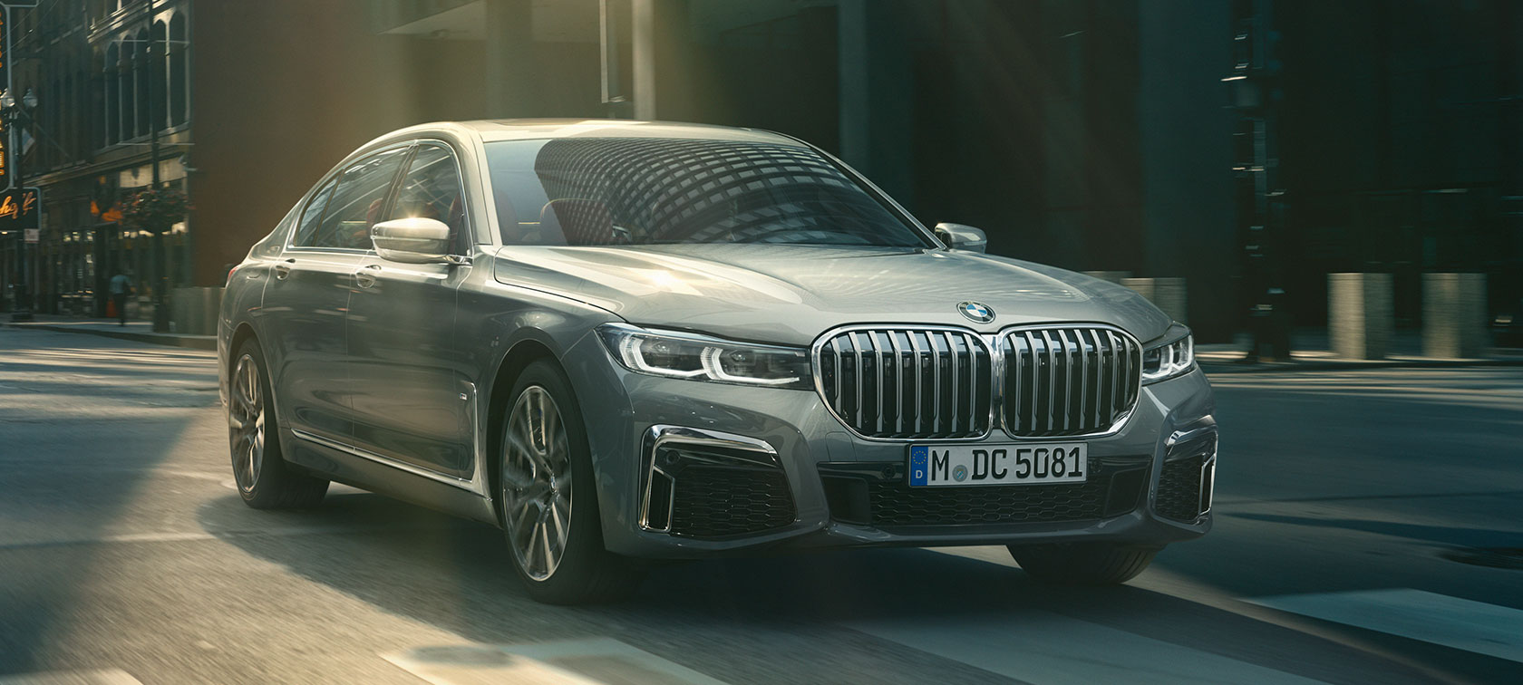 Sivi BMW serije 7 Limuzina, tričetrtinski pogled od spredaj BMW serije 7 Limuzina pri mestni vožnji v tričetrtinskem pogledu od spredaj