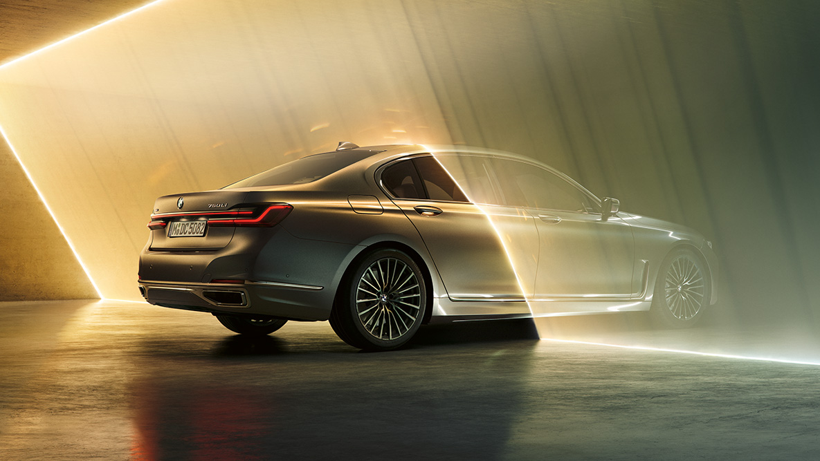 BMW serije 7 Limuzina, G11, G12, 2019, barva Bernina Grey BMW serije 7 Limuzina, G11, G12, 2019, barva Bernina Grey Amber Effect, tričetrtinski pogled od zadaj, obdan z žarki svetlobe