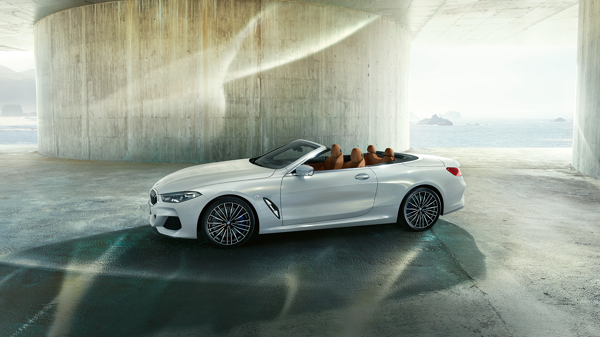BMW M850i xDrive v kovinskem odtenku Mineral White, pogled s strani z odprto mehko streho. BMW M850i xDrive v kovinskem odtenku Mineral White, pogled s strani z odprto mehko streho.