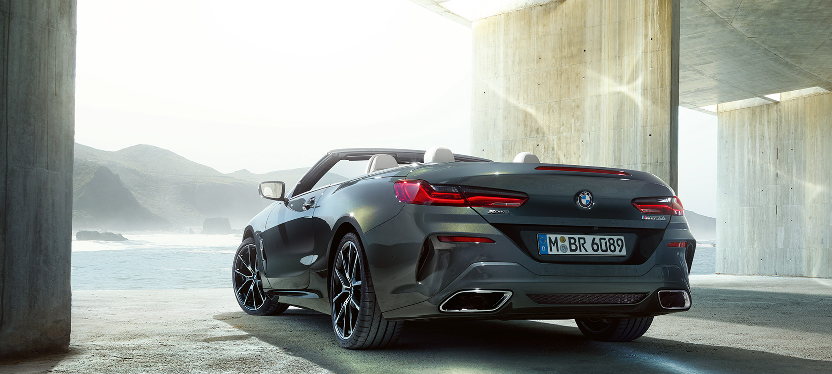 BMW M850i xDrive v kovinskem odtenku Dravit Grey, tričetrtinski pogled od zadaj levo. BMW M850i xDrive v kovinskem odtenku Dravit Grey, tričetrtinski pogled od zadaj levo.