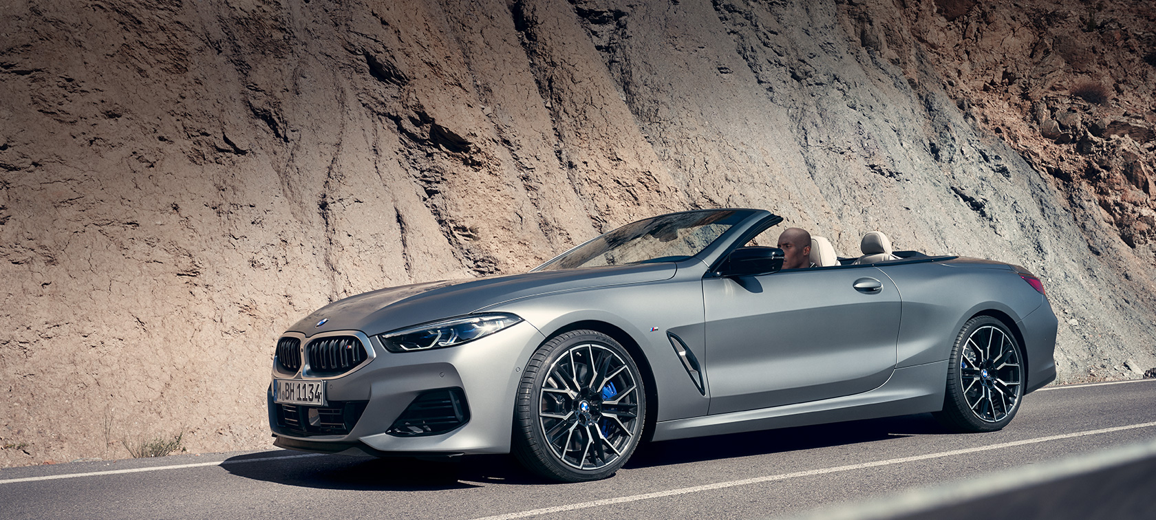 Novi BMW serije 8 Cabrio, G14, LCI, osvežitev 2022, BMW M850i xDrive, lakiranje BMW Individual v kovinski barvi Frozen Pure Grey, tričetrtinski stranski pogled med mirovanjem pred stavbo Novi BMW serije 8 Cabrio, G14, LCI, osvežitev 2022, BMW M850i xDrive, lakiranje BMW Individual v kovinski barvi Frozen Pure Grey, tričetrtinski stranski pogled med mirovanjem pred stavbo