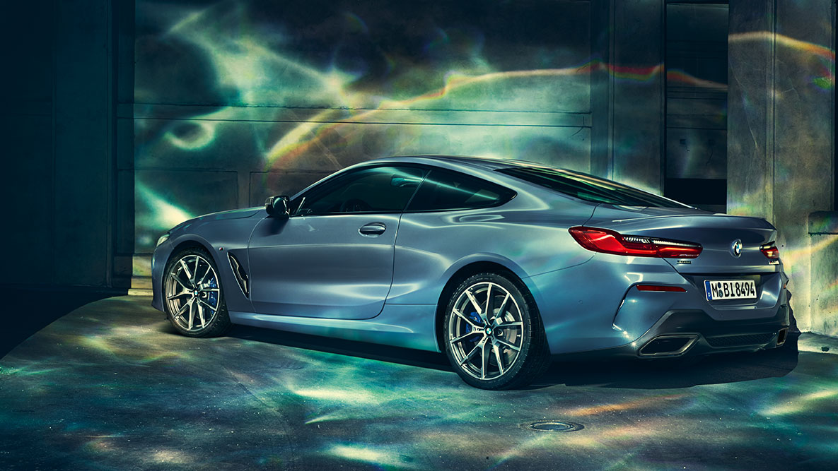 BMW serije 8 Coupé, tričetrtinski posnetek zadka. Tričetrtinski posnetek zadka BMW serije 8 Coupé ponoči pred mestno kuliso.