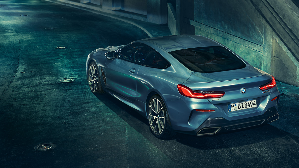 BMW serije 8 Coupé, tričetrtinski posnetek zadka. Tričetrtinski posnetek zadka BMW serije 8 Coupé ponoči pred mestno kuliso.