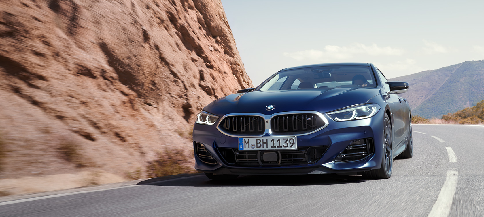 BMW serije 8 Gran Coupé, G16, LCI, osvežitev 2022, lakiranje BMW Individual v kovinski barvi Frozen Tanzanite Blue, tričetrtinski pogled od spredaj med vožnjo po gorski cesti