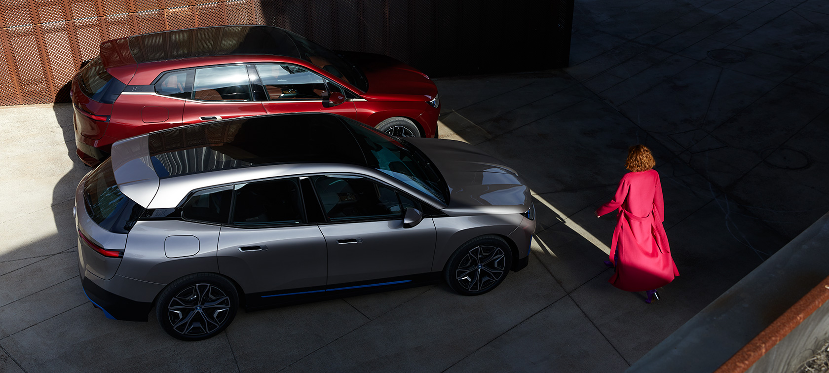 BMW iX, pogled iz ptičje perspektive z manekenko BMW iX, Aventurin Red in Cashmere Silver, i20, pogled iz ptičje perspektive z manekenko