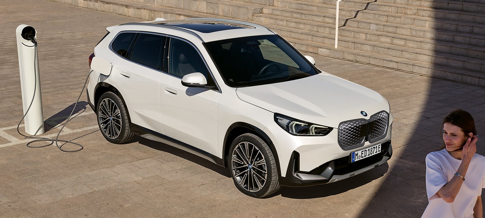 BMW iX1, U11, BEV, stranski pogled, polnjenje BMW iX1, U11, BEV, 2022, kovinska barva Mineral White, dvotretjinski stranski pogled, polnjenje