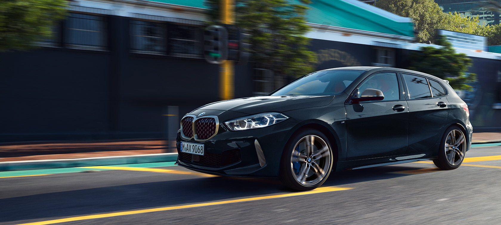 Popolnoma novi BMW M135i xDrive Popolnoma novi BMW M135i xDrive v kovinski barvi Black Sapphire, tričetrtinski stranski pogled med vožnjo.