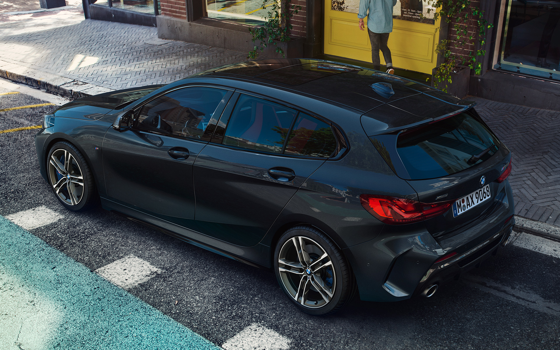BMW M135i xDrive (F40), kovinska barva Black Sapphire, stranski pogled iz ptičje perspektive med parkiranjem