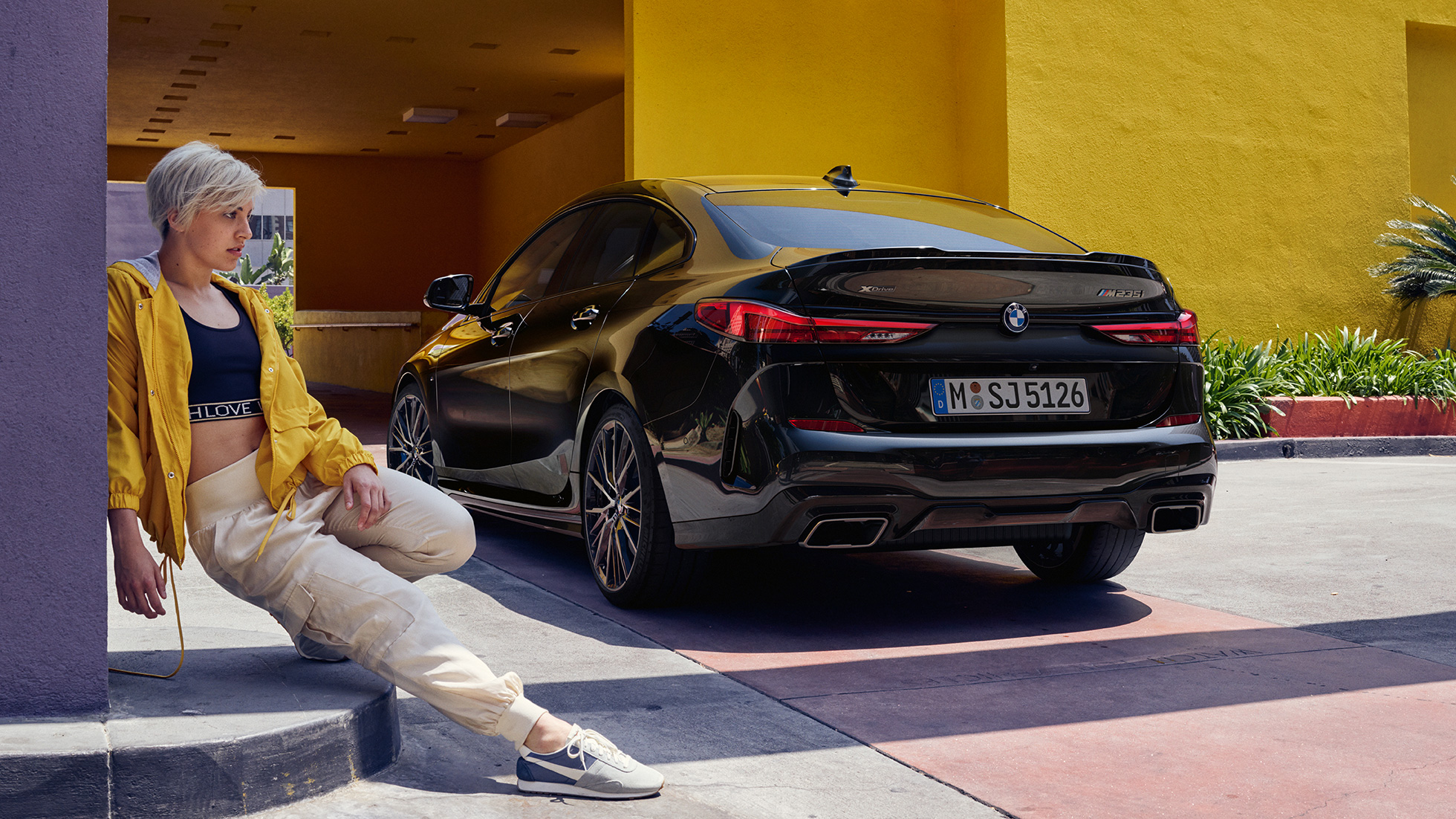 Zadnji del BMW M235i xDrive Gran Coupé Športni zadnji del vozila BMW M235i xDrive Gran Coupé 2020 v kovinski barvi Black Sapphire F44, tričetrtinski pogled od zadaj