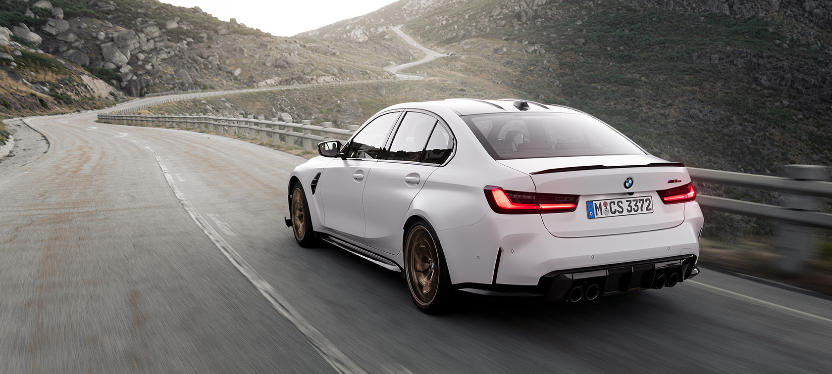 BMW M3 CS, G80, tričetrtinski pogled od zadaj med vožnjo BMW M3 CS, G80, tričetrtinski pogled od zadaj med vožnjo po gorski cesti