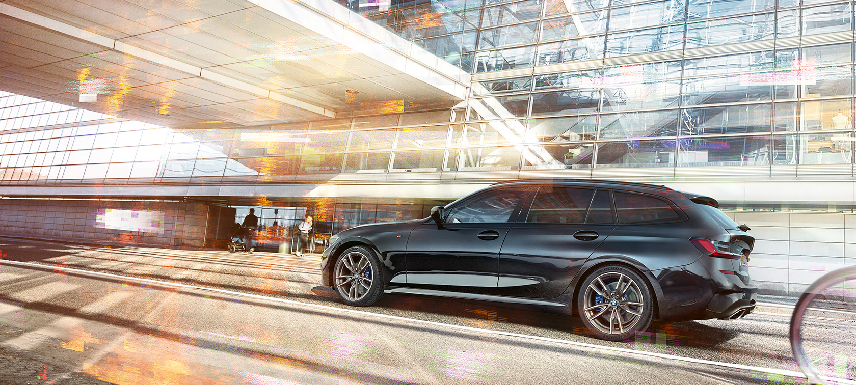 BMW M340i xDrive Touring, stranski posnetek med vožnjo BMW M340i xDrive Touring, stranski posnetek med vožnjo pred stekleno stavbo