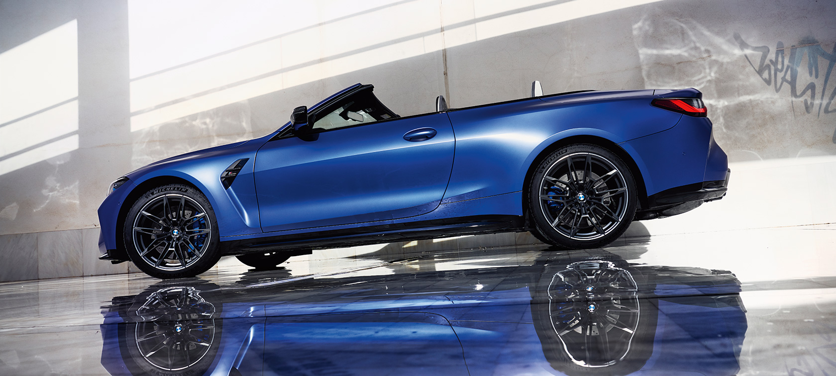 BMW M4 Competition Cabrio z M xDrive, G83, 2021, stranski pogled, posnetek pod nizkim kotom BMW M4 Competition Cabrio z M xDrive, G83, 2021, lakiranje BMW Individual v kovinski barvi Frozen Portimao Blue, stranski pogled med mirovanjem, posnetek pod nizkim kotom