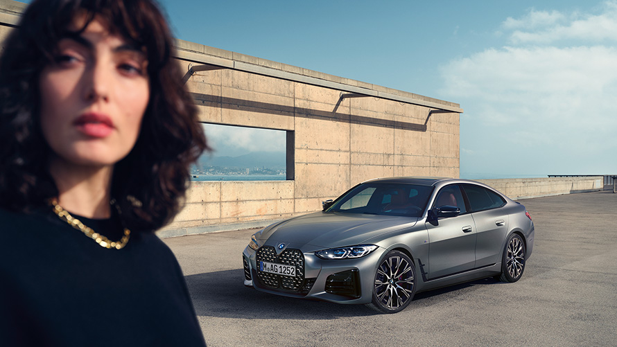 BMW M440i xDrive Gran Coupé, G26, 2021, tričetrtinski pogled od spredaj z manekenko BMW M440i xDrive Gran Coupé, G26, 2021, kovinska barva Frozen Pure Grey, tričetrtinski pogled od spredaj z manekenko
