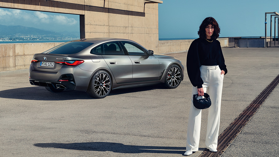 BMW M440i xDrive Gran Coupé, G26, 2021, tričetrtinski pogled od zadaj z manekenko BMW M440i xDrive Gran Coupé, G26, 2021, kovinska barva Frozen Pure Grey, tričetrtinski pogled od zadaj z manekenko