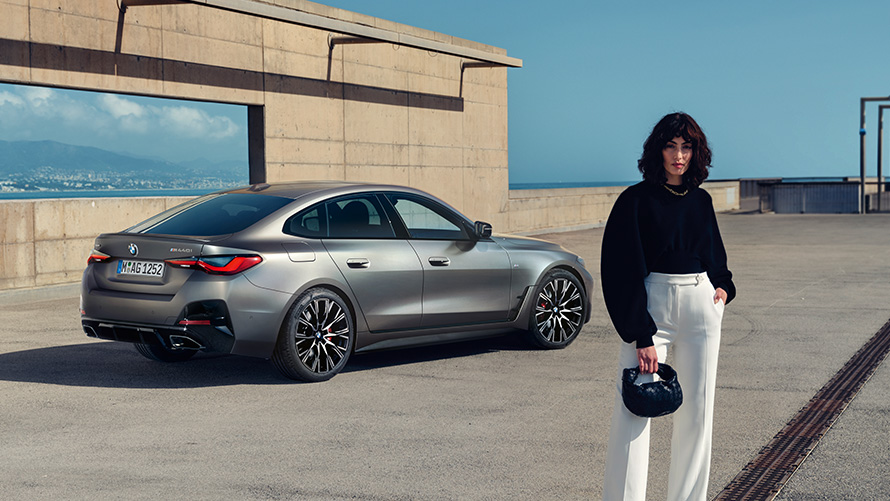 BMW M440i xDrive Gran Coupé, G26, 2021, tričetrtinski pogled od zadaj z manekenko BMW M440i xDrive Gran Coupé, G26, 2021, tričetrtinski pogled od zadaj z manekenko