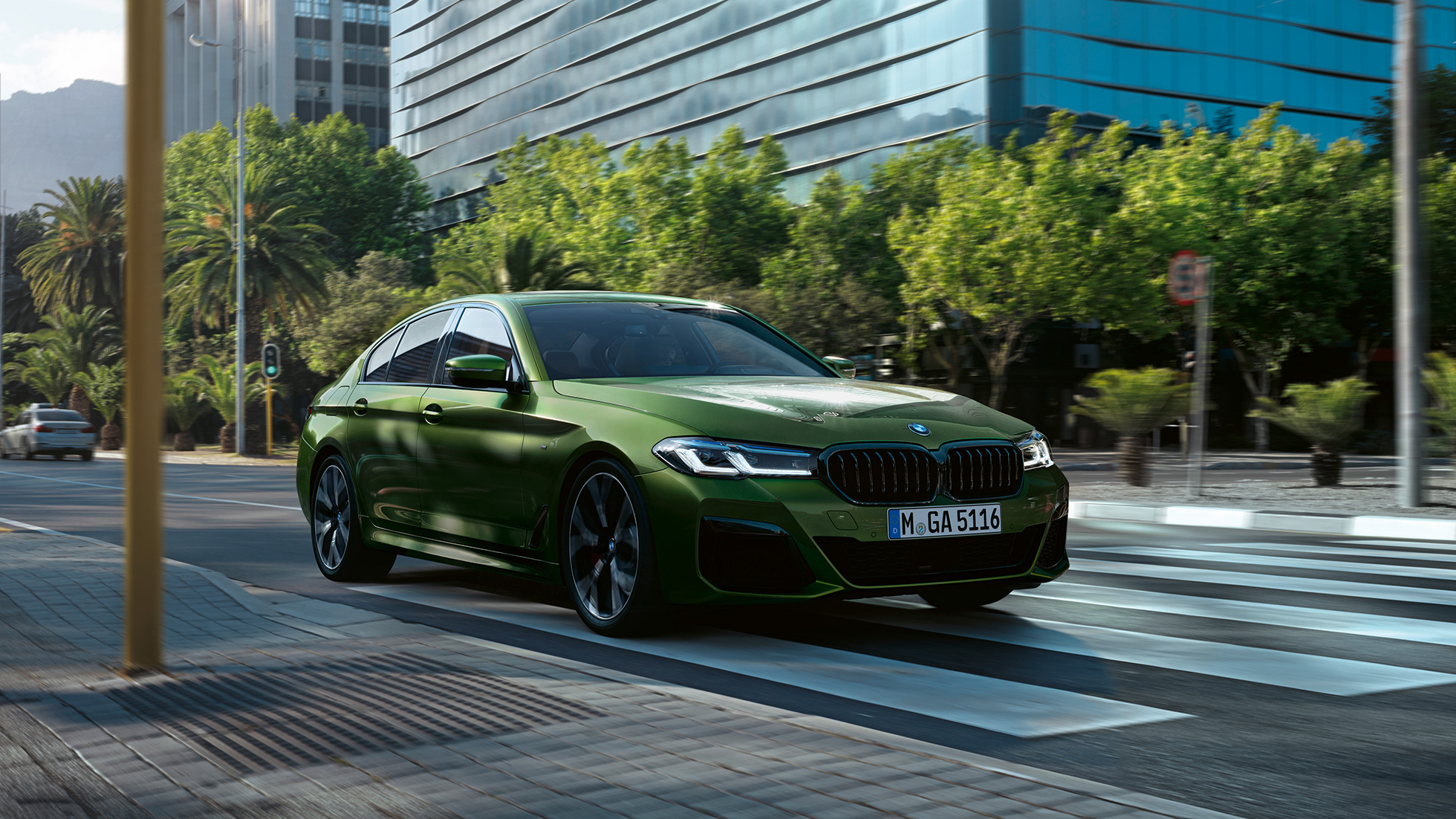 BMW M550i xDrive Limuzina, G30 LCI, osvežitev 2020, tričetrtinski pogled od spredaj med vožnjo BMW M550i xDrive Limuzina, G30 LCI, osvežitev 2020, BMW Individual, kovinska barva Verde Ermes, tričetrtinski pogled od spredaj med vožnjo po mestnem središču