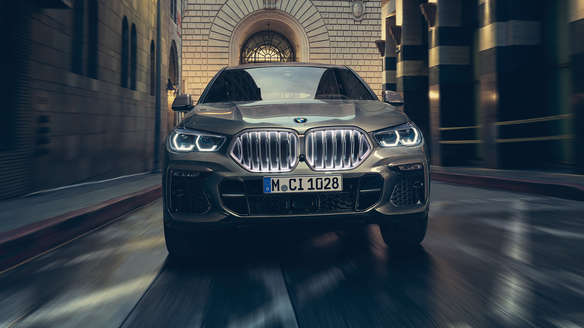 BMW X6 M50i, ledvička BMW Iconic Glow. BMW X6 M50i, pogled od spredaj v mestnem okolju.