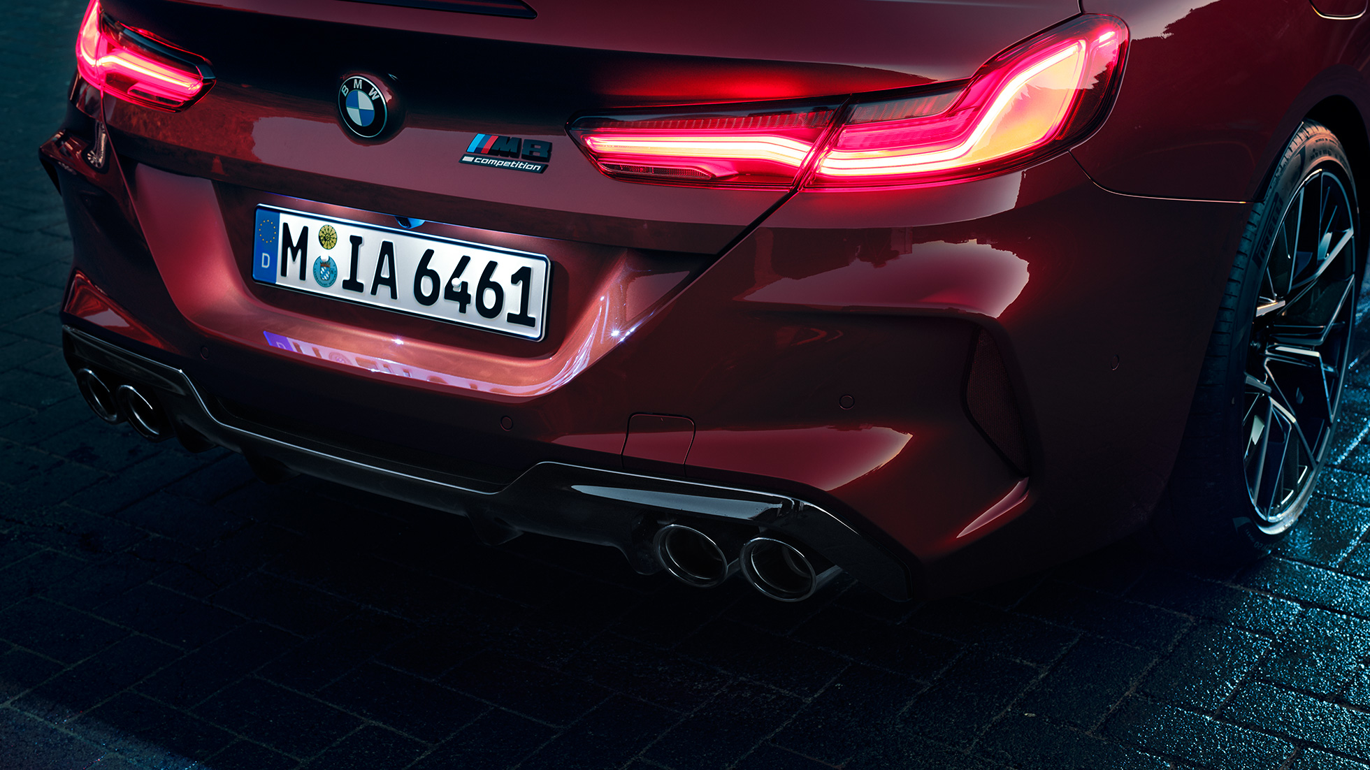 BMW M8 Competition Cabrio, povečan posnetek zadnjega dela. BMW M8 Competition Cabrio v kovinski barvi Motegi Red, povečan posnetek zadnjega dela z zadnjimi LED lučmi in znamko M8 Competition.
