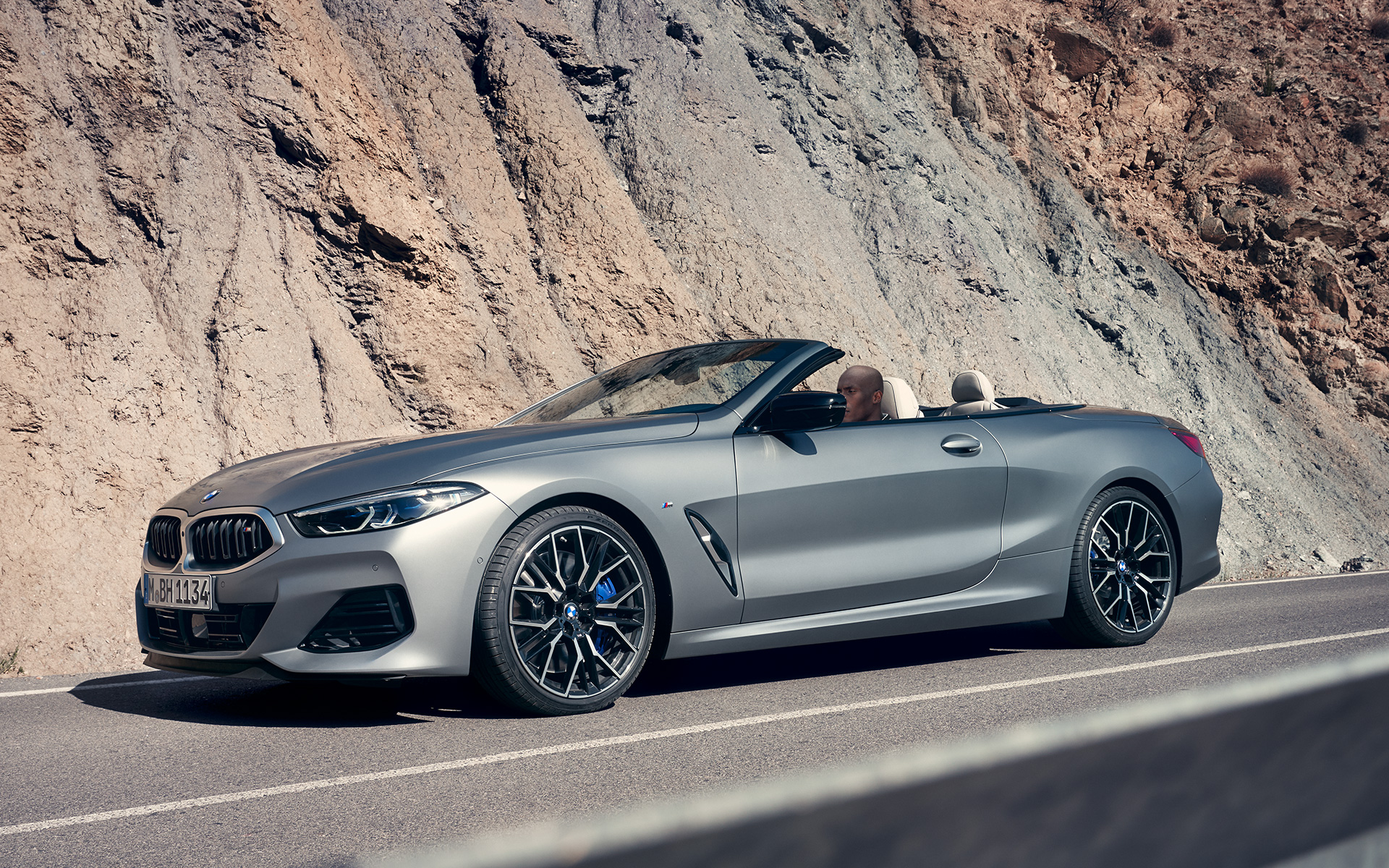 BMW M850i xDrive Cabrio, G14, LCI, osvežitev 2022, tričetrtinski pogled od spredaj BMW M850i xDrive Cabrio, G14, LCI, osvežitev 2022, lakiranje BMW Individual v kovinski barvi Frozen Pure Grey, tričetrtinski pogled od spredaj med vožnjo pred pečino