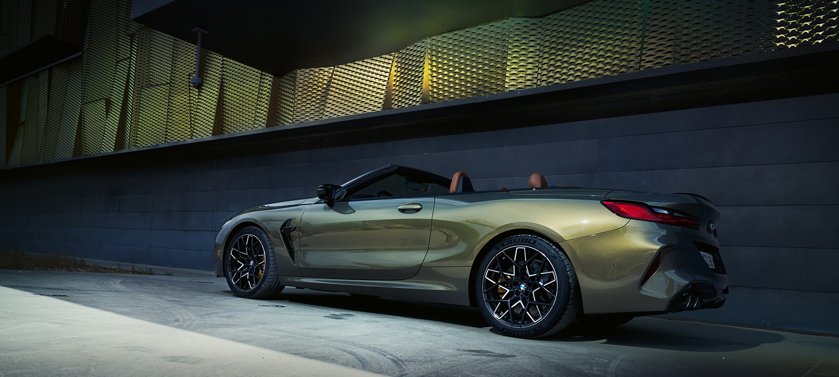 BMW M8 Competition Cabrio, F91, LCI, osvežitev 2022, lakiranje BMW Individual v kovinski barvi Brass, tričetrtinski stranski pogled med mirovanjem pred steno