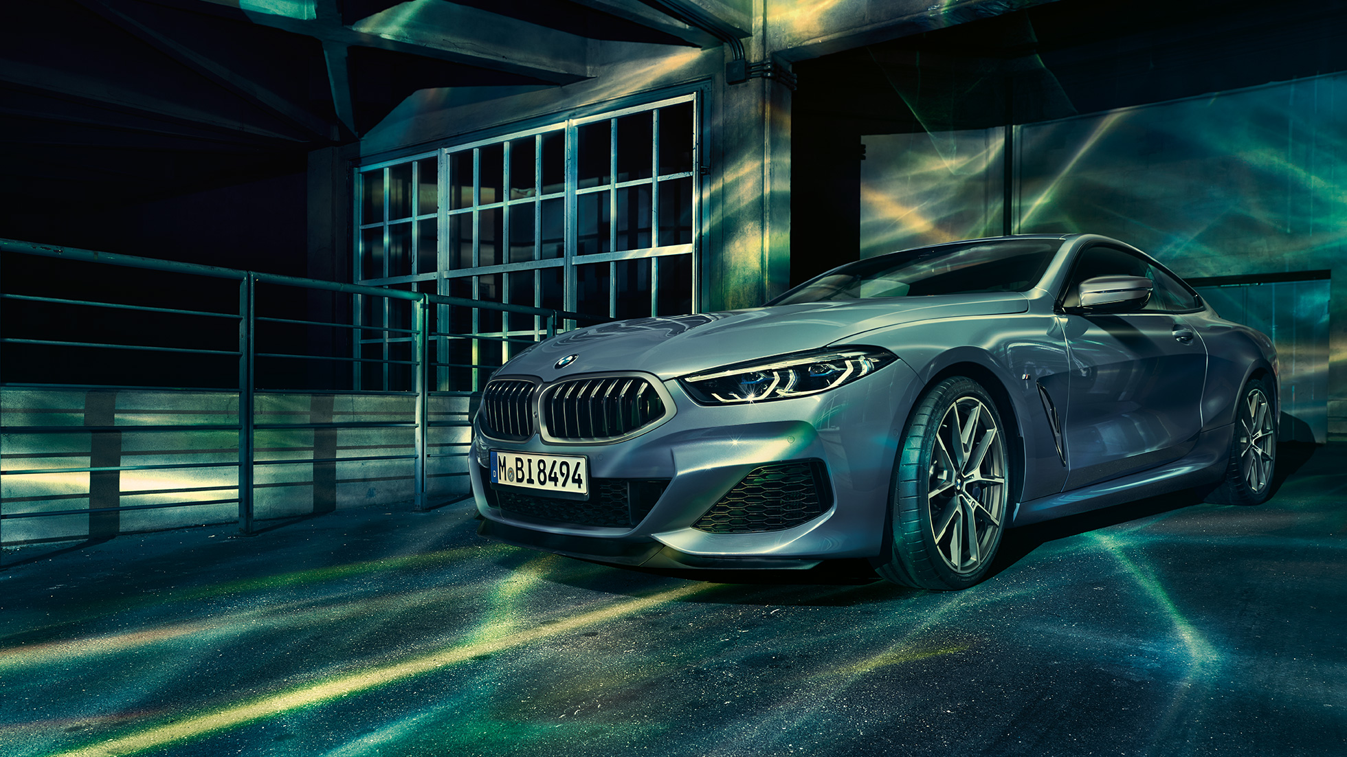 BMW M850i xDrive Coupé, v sprednjem polprofilu. BMW M850i xDrive Coupé v kovinski barvi Barcelona Blue, v sprednjem polprofilu, parkiran pred stavbo.