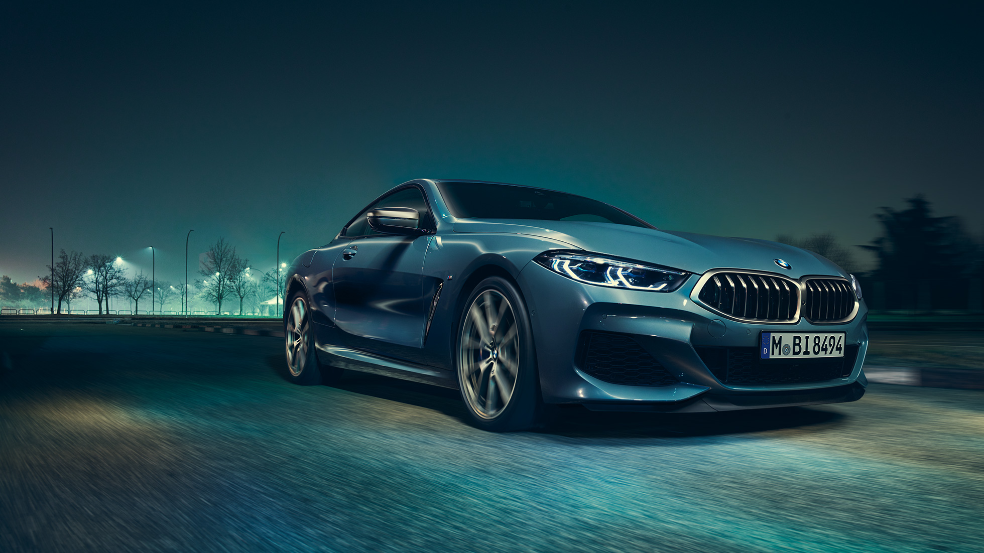 BMW M850i xDrive Coupé, v sprednjem polprofilu z leve strani. BMW M850i xDrive Coupé v kovinski barvi Barcelona Blue, v sprednjem polprofilu, med nočno vožnjo.