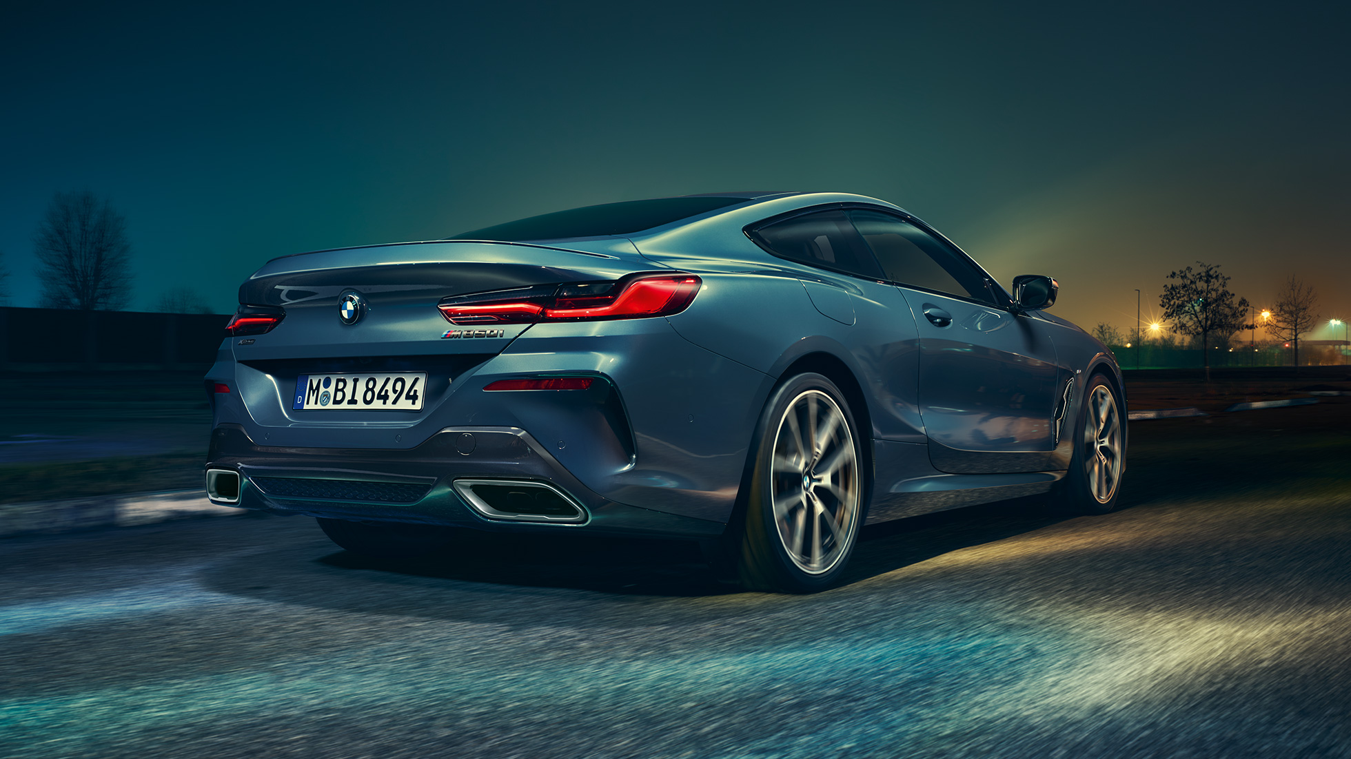 BMW M850i xDrive Coupé, z zadnje strani. BMW M850i xDrive Coupé v kovinski barvi Barcelona Blue, z zadnje strani, med nočno vožnjo.