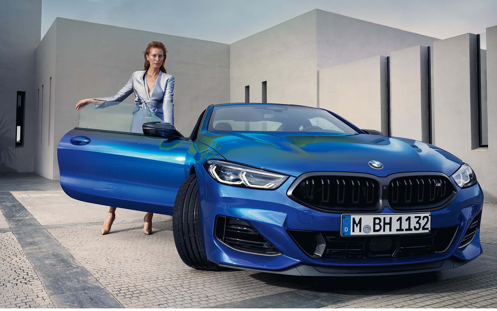 BMW M850i xDrive Coupé, G15, LCI, osvežitev 2022, kovinska barva M Portimao Blue, pogled od spredaj med mirovanjem z manekenko pri odprtih vratih
