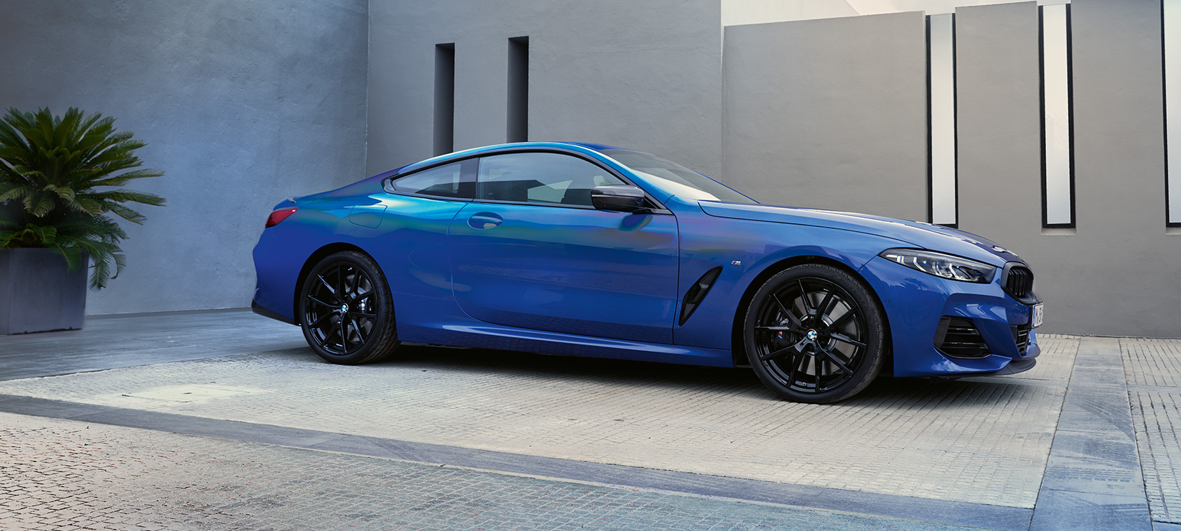 BMW M850i xDrive Coupé, G15, LCI, osvežitev 2022, kovinska barva M Portimao Blue, stranski pogled med mirovanjem pred stavbo