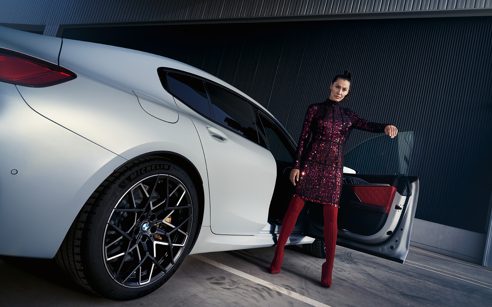 BMW M8 Competition Gran Coupé, F93, LCI, 2022, tričetrtinski pogled od zadaj z manekenko, posnetek pod nizkim kotom BMW M8 Competition Gran Coupé, F93, LCI, osvežitev 2022, lakiranje BMW Individual v kovinski barvi Frozen Brilliant White, tričetrtinski pogled od zadaj z manekenko, posnetek pod nizkim kotom