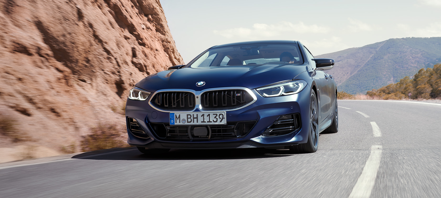 Novi BMW M850i xDrive Gran Coupé, F93 ,LCI, osvežitev 2022, tričetrtinski pogled od spredaj med vožnjo Novi BMW M850i xDrive Gran Coupé, F93 ,LCI, osvežitev 2022, lakiranje BMW Individual v kovinski barvi Frozen Tanzanite Blue, tričetrtinski pogled od spredaj med vožnjo skozi ovinek