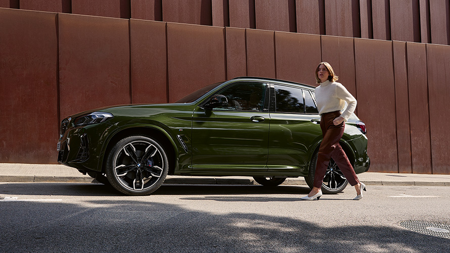 BMW X3 M40i, G01, LCI, osvežitev 2021, kovinska barva Malachite Green, stranski pogled z manekenko