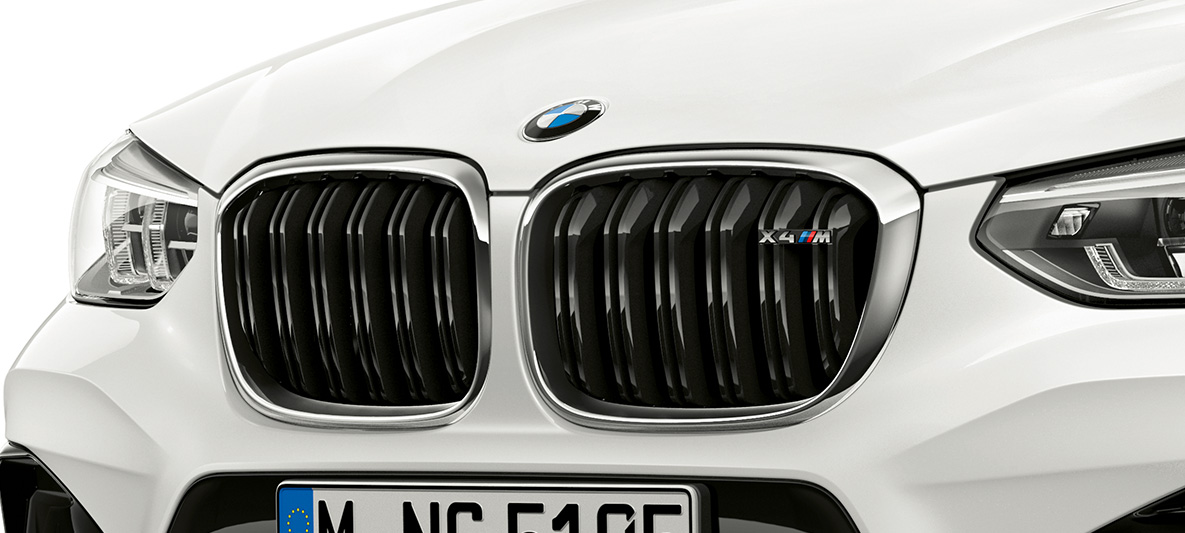 BMW X4 M, ledvičasta maska M. BMW X4 M v barvi Alpine White, zunanjost, sprednji del, ledvičasta maska M s kromiranimi poudarki in oznako modela.